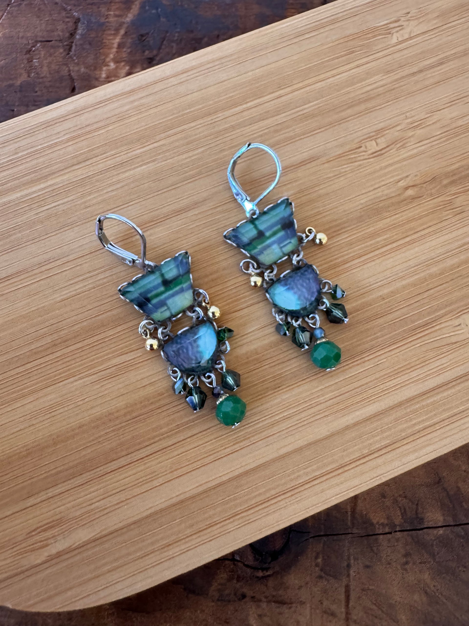 Pair of earrings with blue and green stones on a wooden surface