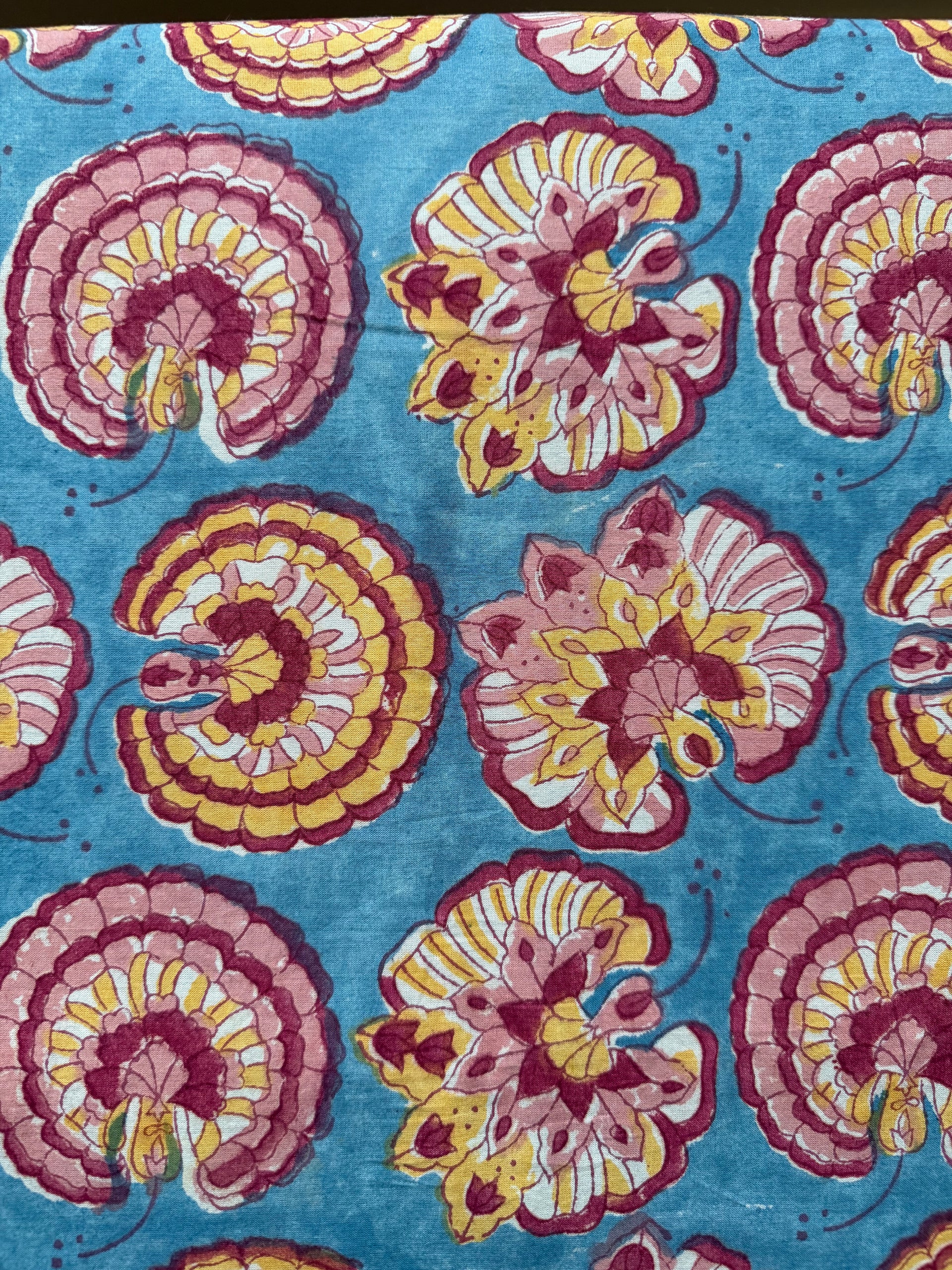 Floral patterned fabric with pink and yellow flowers on a blue background