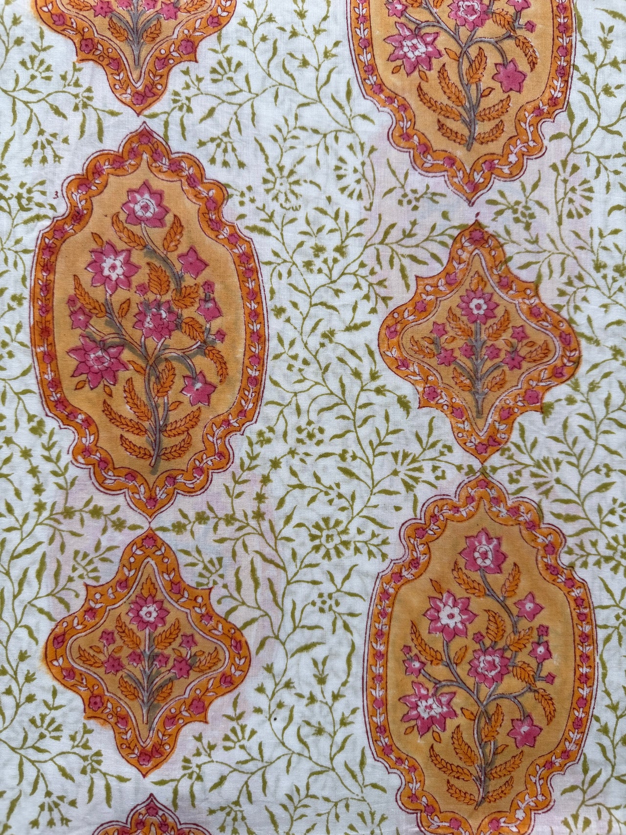 Decorative fabric with floral and leaf patterns in orange, pink, and green on a white background.