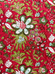 Floral patterned fabric with green, white, and pink flowers on a red background