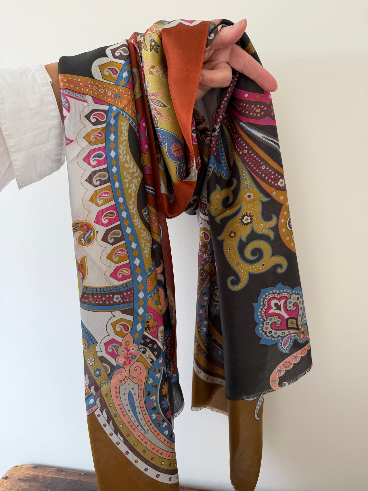 Colorful patterned scarf held by a person against a white background