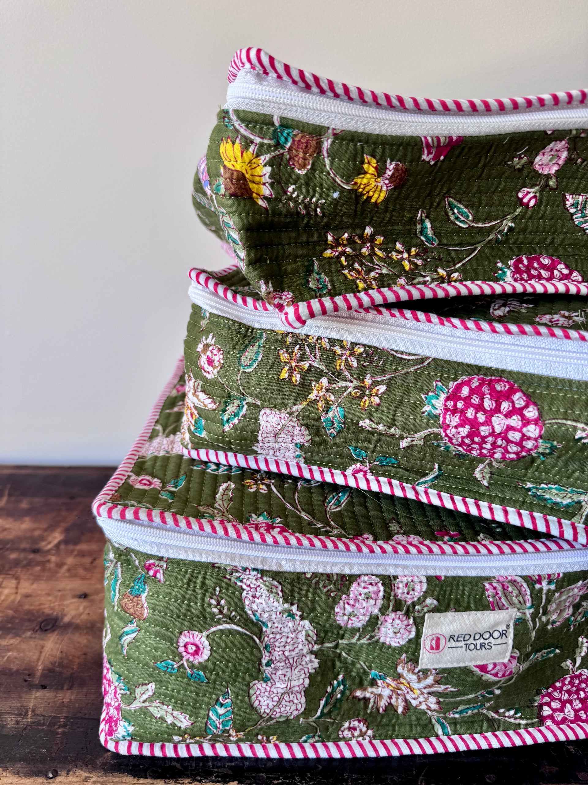 Stack of floral-patterned storage bins with a visible brand label on a wooden surface.